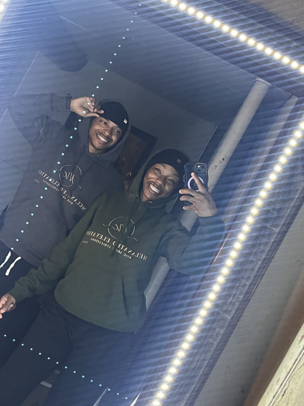 Two community members wearing Melanated Elevation hoodies in a mirror portrait