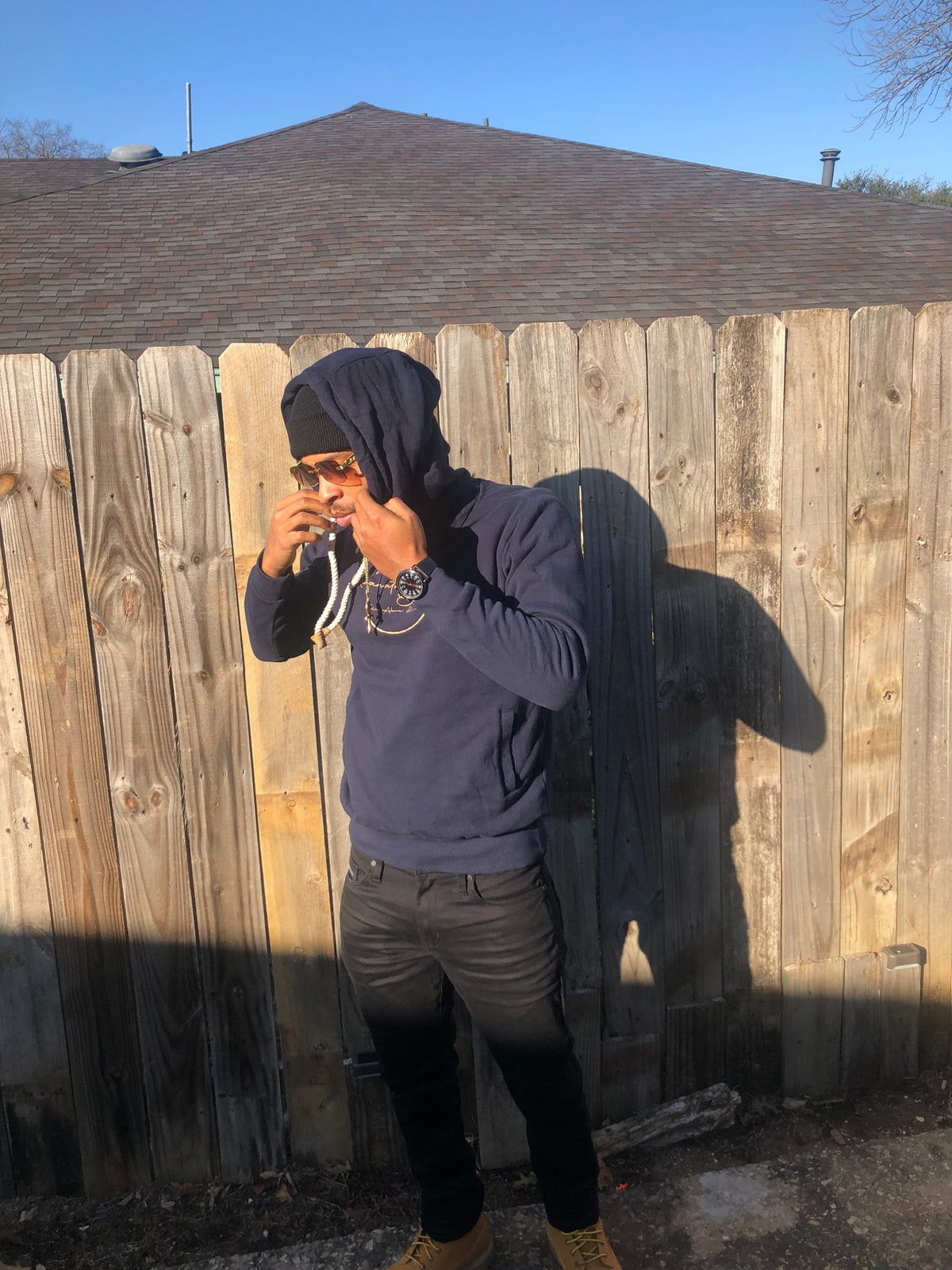Melanated Elevation founder outdoors in a navy hoodie, beanie, and sunglasses